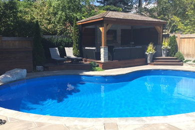 Foto de piscina con fuente alargada clásica de tamaño medio tipo riñón en patio trasero con adoquines de piedra natural