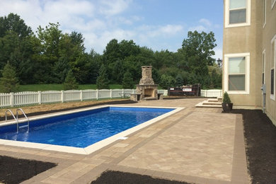 Diseño de piscina alargada actual de tamaño medio rectangular en patio trasero con adoquines de hormigón