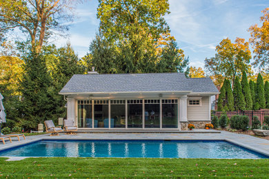 Ejemplo de casa de la piscina y piscina natural clásica grande rectangular en patio trasero con adoquines de piedra natural