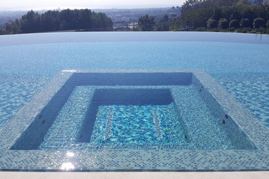 Imagen de piscinas y jacuzzis infinitos actuales grandes rectangulares en patio trasero con suelo de baldosas