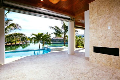 Large beach style backyard tile and rectangular infinity hot tub photo in Miami