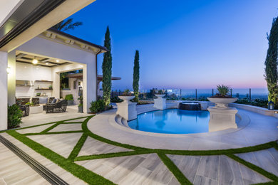 Ejemplo de piscina clásica de tamaño medio redondeada en patio trasero con paisajismo de piscina y adoquines de piedra natural