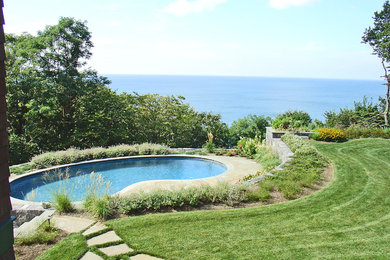 Inspiration for a large traditional back custom shaped natural swimming pool in New York with concrete paving.