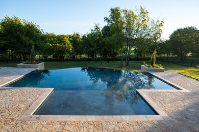 Modelo de piscina alargada clásica grande a medida en patio trasero con adoquines de hormigón