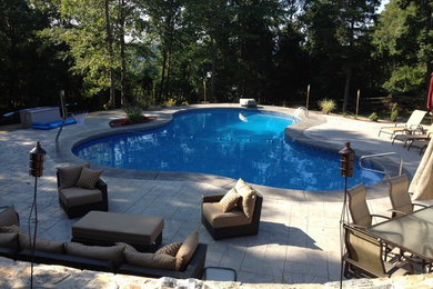 Large minimalist backyard stamped concrete and custom-shaped pool photo in Bridgeport