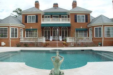 Imagen de piscina elevada tradicional grande a medida en patio trasero con adoquines de piedra natural