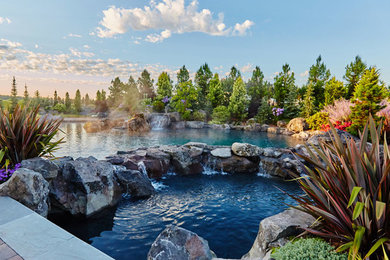 Imagen de piscina con fuente natural actual grande a medida en patio trasero con adoquines de piedra natural