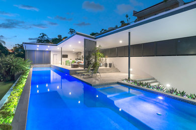 На фото: огромный наземный, прямоугольный бассейн на заднем дворе в стиле модернизм с домиком у бассейна и покрытием из плитки с