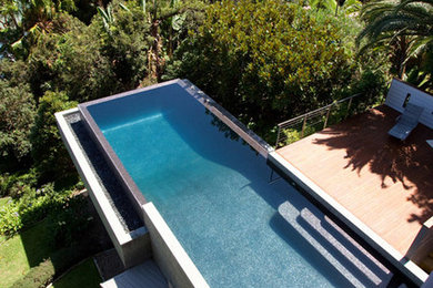 Cette image montre un très grand couloir de nage arrière minimaliste sur mesure avec une terrasse en bois.