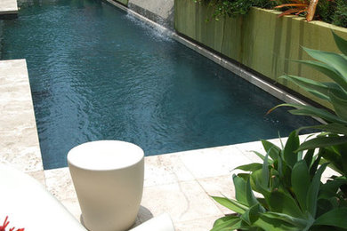 Modelo de piscina con fuente moderna de tamaño medio rectangular en patio trasero con suelo de baldosas