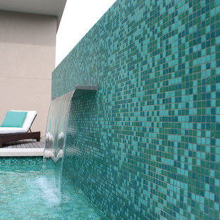 Esempio di una grande piscina minimal personalizzata dietro casa con fontane e pedane