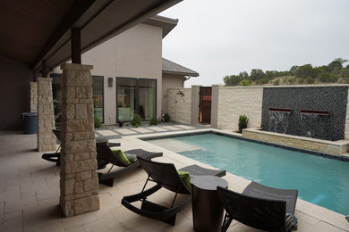 Ejemplo de piscina con fuente alargada contemporánea de tamaño medio rectangular en patio trasero con adoquines de hormigón