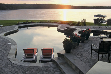 Diseño de piscinas y jacuzzis alargados tradicionales de tamaño medio a medida en patio trasero con adoquines de ladrillo