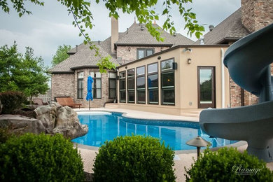 Imagen de piscina con tobogán alargada clásica renovada de tamaño medio a medida en patio trasero con suelo de hormigón estampado