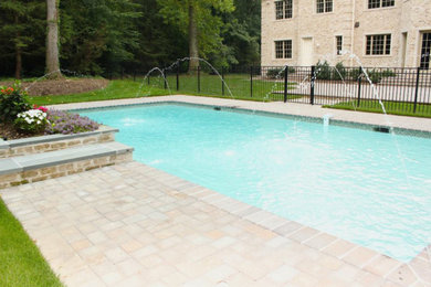 Example of a mid-sized backyard stamped concrete and rectangular lap pool fountain design in New York