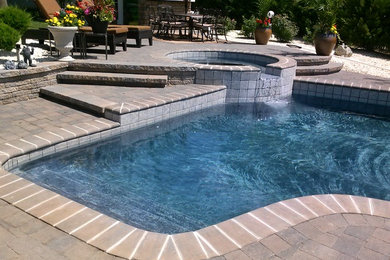 Example of a classic backyard brick and custom-shaped lap hot tub design in Orange County