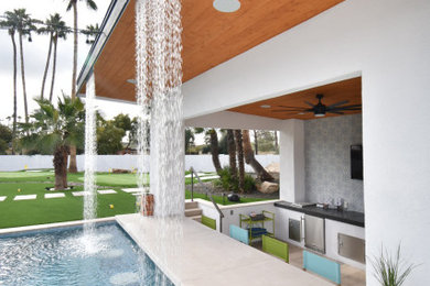 Diseño de piscina moderna grande a medida en patio trasero con adoquines de piedra natural
