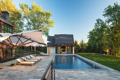 Modelo de casa de la piscina y piscina clásica renovada en patio trasero con adoquines de piedra natural