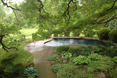 Modelo de piscina con fuente natural tradicional de tamaño medio a medida en patio trasero con adoquines de hormigón