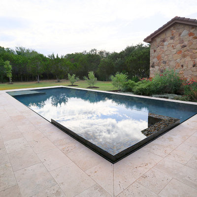 Large tuscan backyard rectangular and stone infinity hot tub photo in Austin
