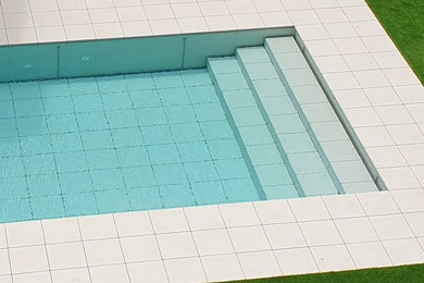 Foto de piscina alargada minimalista de tamaño medio a medida con suelo de baldosas