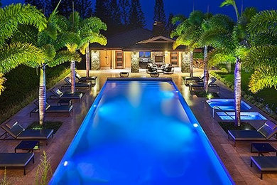 Diseño de piscinas y jacuzzis exóticos de tamaño medio rectangulares en patio trasero con adoquines de piedra natural