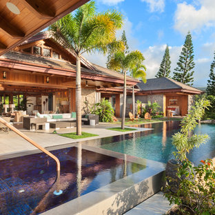 Esempio di una grande piscina a sfioro infinito tropicale rettangolare dietro casa con una vasca idromassaggio e lastre di cemento