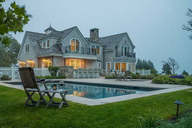 Inspiration for a nautical back rectangular natural swimming pool in Boston with natural stone paving.