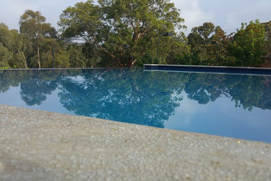 Foto de piscina alargada minimalista de tamaño medio rectangular en patio trasero con adoquines de piedra natural