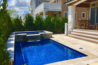 This is an example of a small classic back rectangular hot tub in New York with natural stone paving.