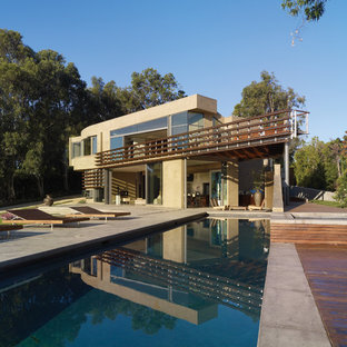Esempio di una piscina monocorsia moderna rettangolare di medie dimensioni e dietro casa con lastre di cemento e fontane