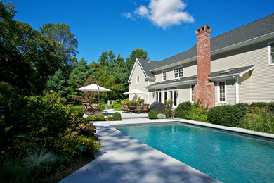 Ejemplo de piscina natural de estilo americano grande rectangular en patio trasero con adoquines de hormigón