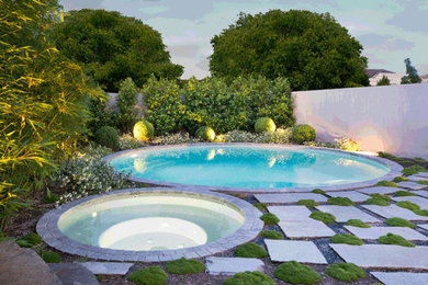 Modern inredning av en stor rund pool framför huset, med granitkomposit