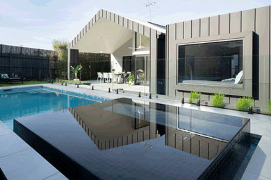 Ejemplo de piscinas y jacuzzis alargados minimalistas grandes rectangulares en patio trasero con adoquines de hormigón