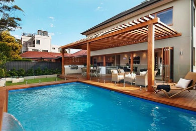 Foto de piscina con fuente alargada contemporánea de tamaño medio rectangular en patio trasero con entablado