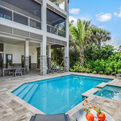 Island style backyard custom-shaped hot tub photo in Miami
