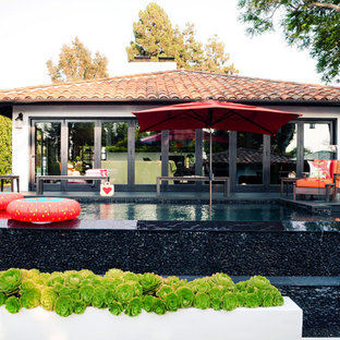 Foto di una piscina a sfioro infinito mediterranea rettangolare di medie dimensioni e dietro casa con pedane