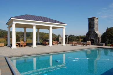 Ejemplo de piscina clásica extra grande rectangular en patio lateral con adoquines de hormigón