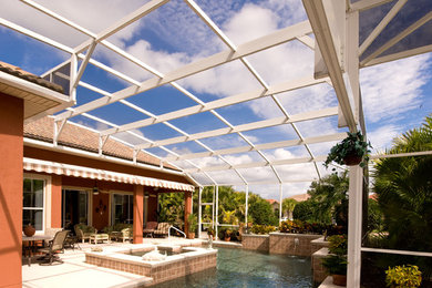 Foto de piscinas y jacuzzis alargados tradicionales grandes en forma de L en patio trasero con losas de hormigón