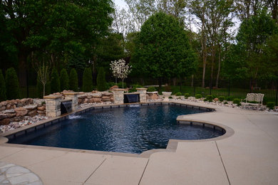 Diseño de piscina con fuente alargada tradicional grande a medida en patio trasero con losas de hormigón
