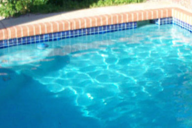 Diseño de piscina rectangular en patio trasero con adoquines de ladrillo