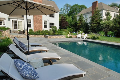 Foto de piscina con fuente tradicional renovada rectangular en patio trasero con adoquines de piedra natural
