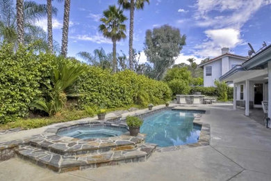 Inspiration for a mid-sized contemporary backyard stone and rectangular aboveground hot tub remodel in Orange County
