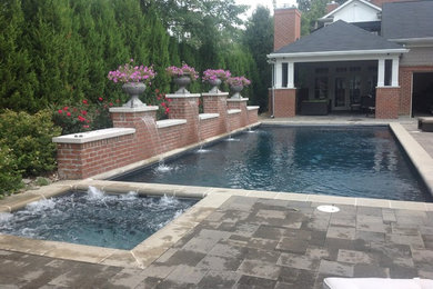 Ejemplo de piscina clásica de tamaño medio rectangular en patio con adoquines de hormigón
