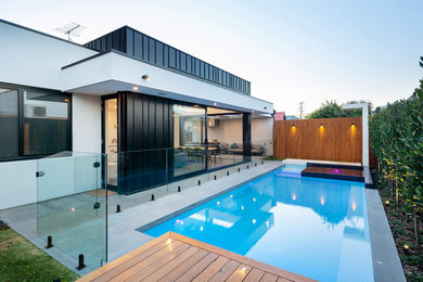 Exemple d'un couloir de nage arrière tendance rectangle avec un bain bouillonnant et une terrasse en bois.