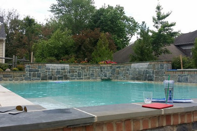 Imagen de piscina con fuente alargada tradicional grande rectangular en patio trasero con adoquines de hormigón