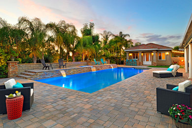 Foto de piscina con fuente tradicional renovada extra grande rectangular en patio trasero con adoquines de piedra natural