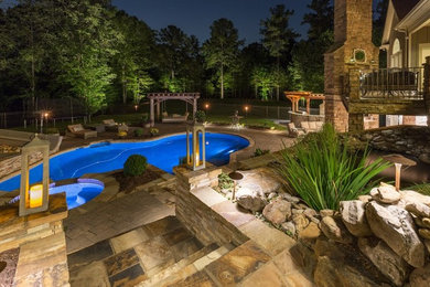 Example of a huge arts and crafts backyard stone and custom-shaped hot tub design in Atlanta