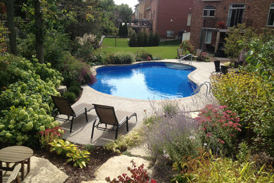 Imagen de piscina clásica renovada grande a medida en patio trasero con granito descompuesto