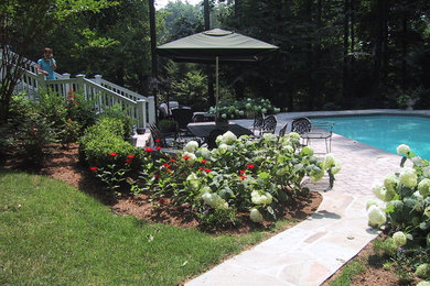 Ejemplo de piscina alargada clásica grande rectangular en patio trasero con adoquines de ladrillo